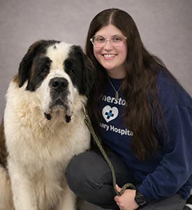 Taryn posing for a picture with a dog on grey background