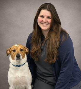 Emma posing for a picture with a dog on grey background