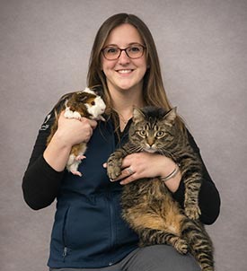 Jessica P. posing for a picture with a cat and guinea pig on grey background
