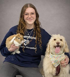 Mallory posing for a picture with a dog and bunny on grey background