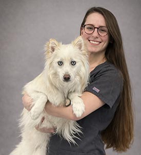 Jenna posing for a picture with a dog on grey background
