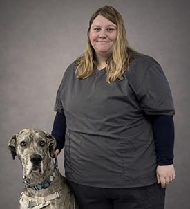 Kimberly posing for a picture with a dog on grey background