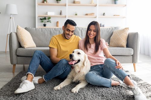 couple-sitting-on-the-living-room-floor-with-their-golden-retriever-dog
