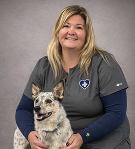Lindsay posing for a picture with a dog on grey background